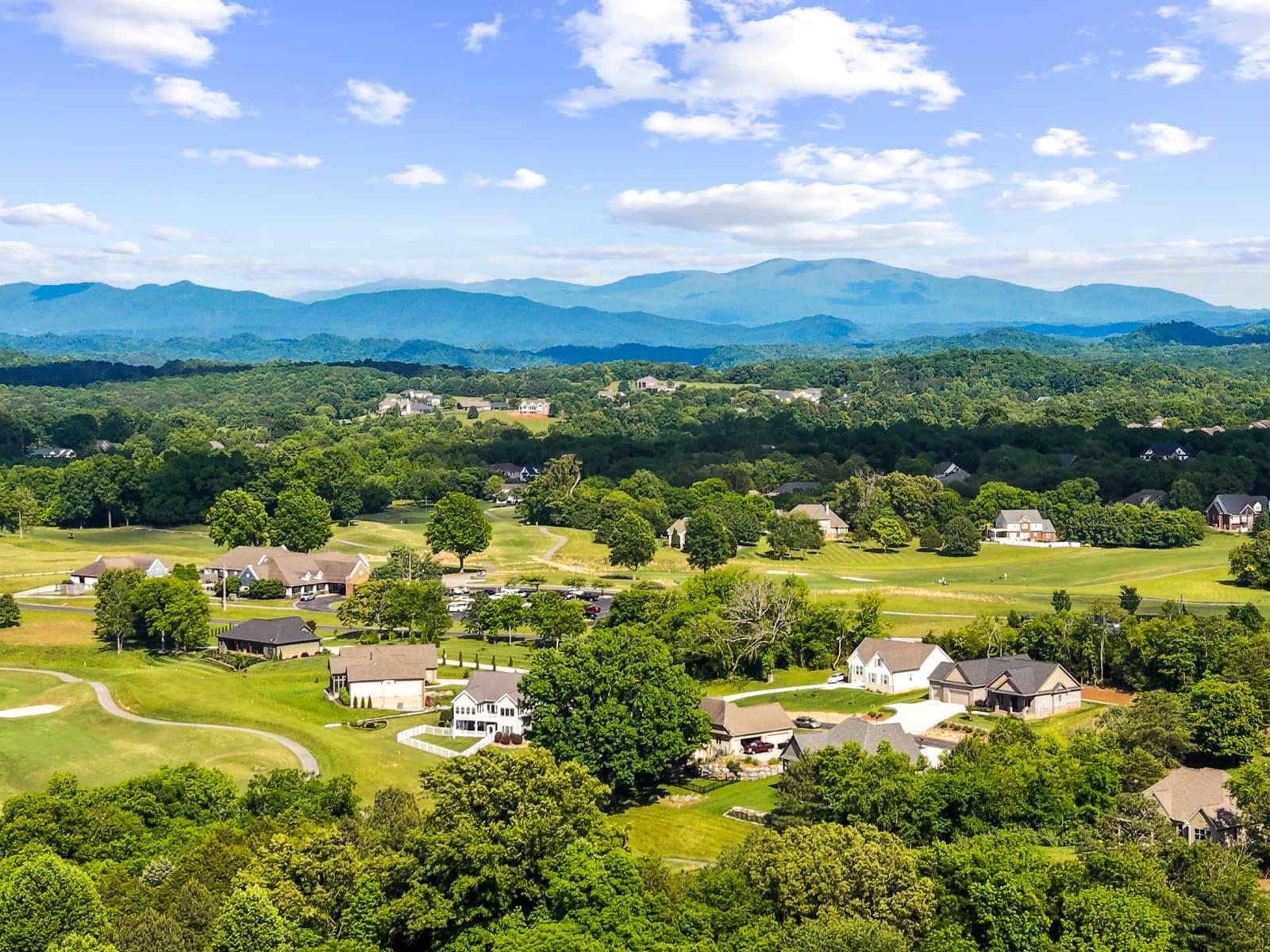 High-altitude aerial photo of a hillside community and open acreage