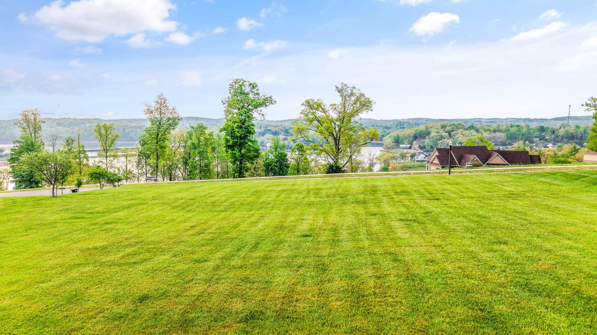 Ground-level view across a mown vacant estate lot toward the lake