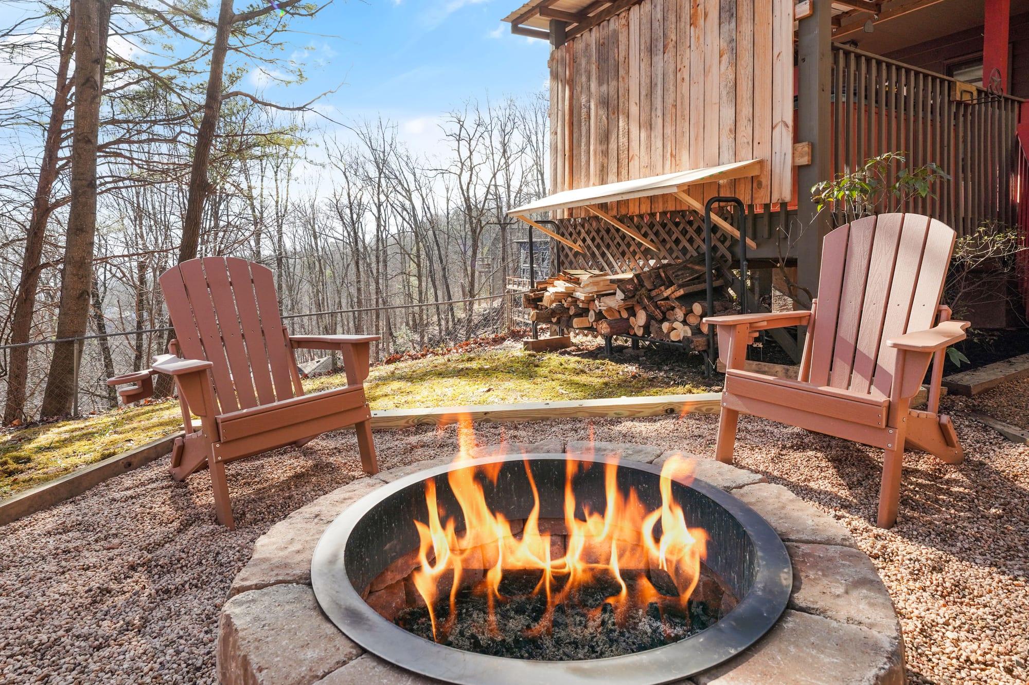Lit stone fire pit with adirondack chairs beside the cabin