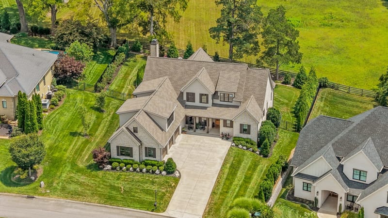 Overhead drone view of a custom estate with manicured landscaping and wide driveway