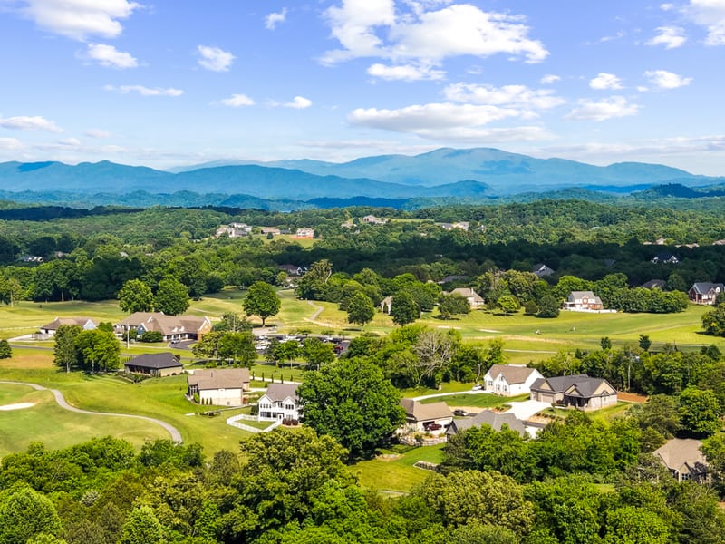 Drone view of a golf-course community with the Smoky Mountains on the horizon
