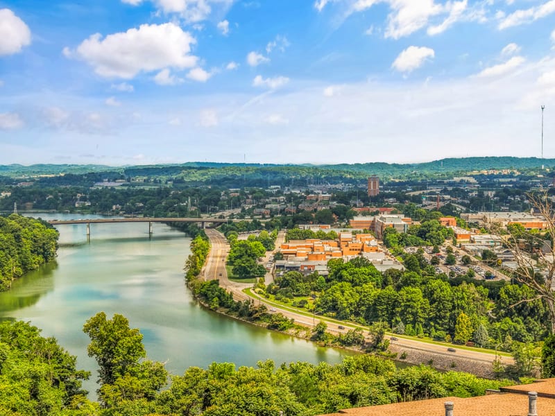 Drone panorama of a river bend with a bridge and city skyline in the distance