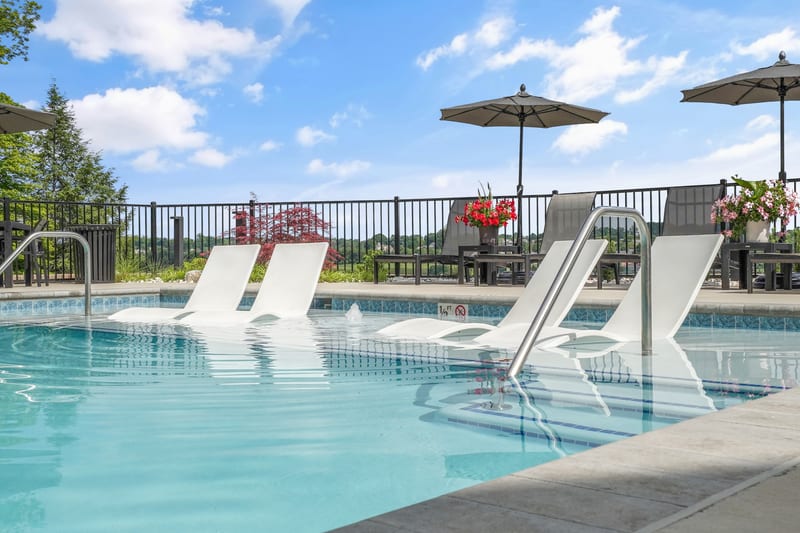 Resort-style community pool with in-water loungers and umbrellas