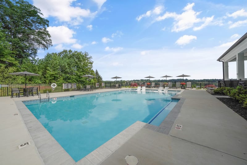 Community pool terrace with loungers looking over a green valley