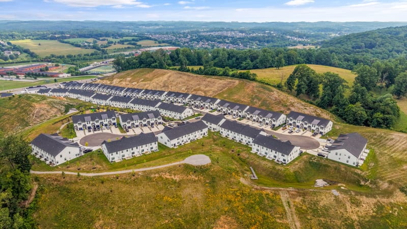 Drone aerial of the community against a valley and farm horizon