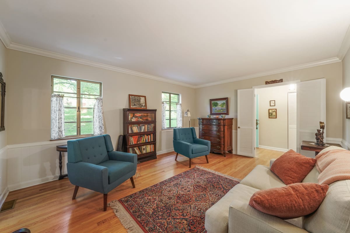 Living room with blue armchairs, oriental rug, and gallery walls