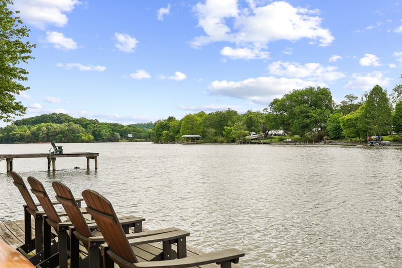 Adirondack chairs facing a wide lake with a private dock at the shoreline