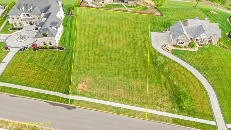 Drone aerial of a vacant estate lot with yellow marketing lot lines drawn over the grass