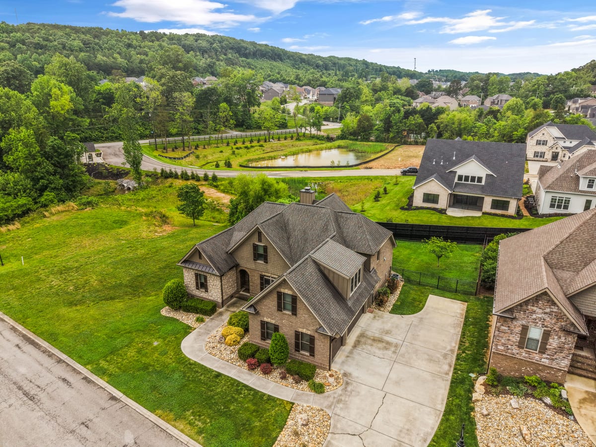 Drone aerial of the home nestled in rolling hills near a community pond