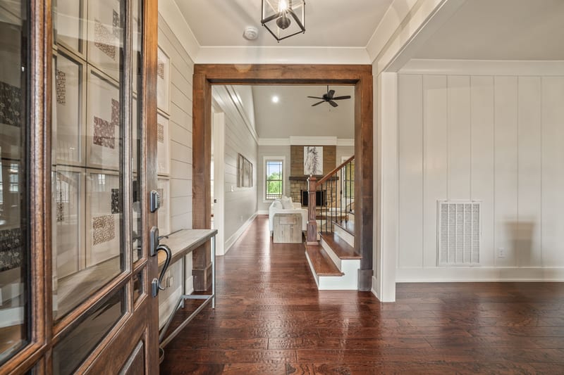 Entry hall with steel-frame glass door, hardwood floors, and staircase beyond