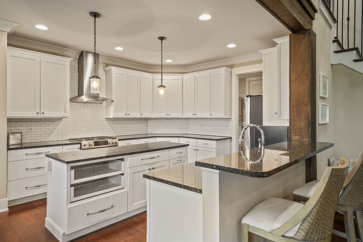 Kitchen with paired islands, vent hood, granite, and a timber beam