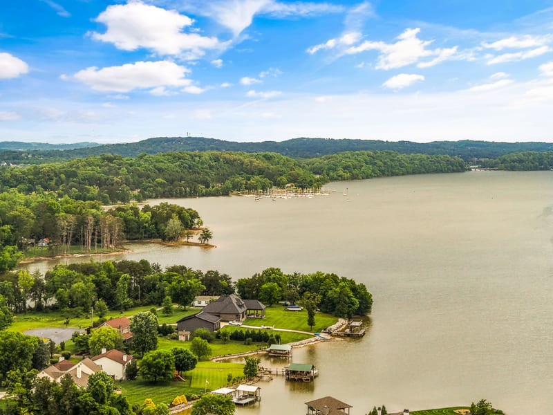 Drone aerial across the lake toward a marina and wooded shoreline