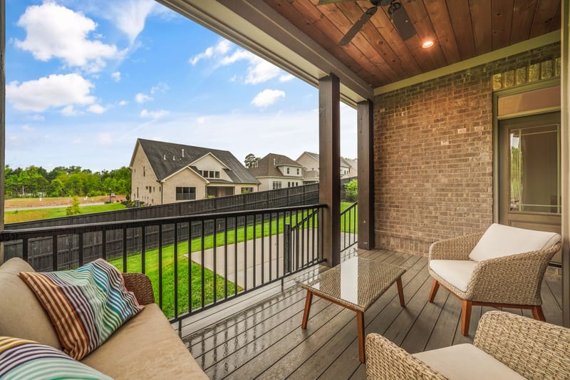 Covered porch with wood ceiling, wicker seating, and pasture view