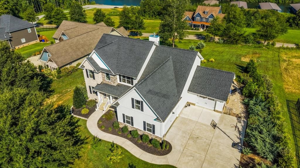 Drone aerial over the farmhouse roof and curved driveway (detail crop)