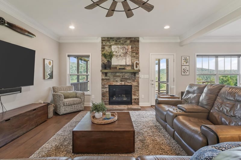 Great room with a stone fireplace flanked by tall view windows