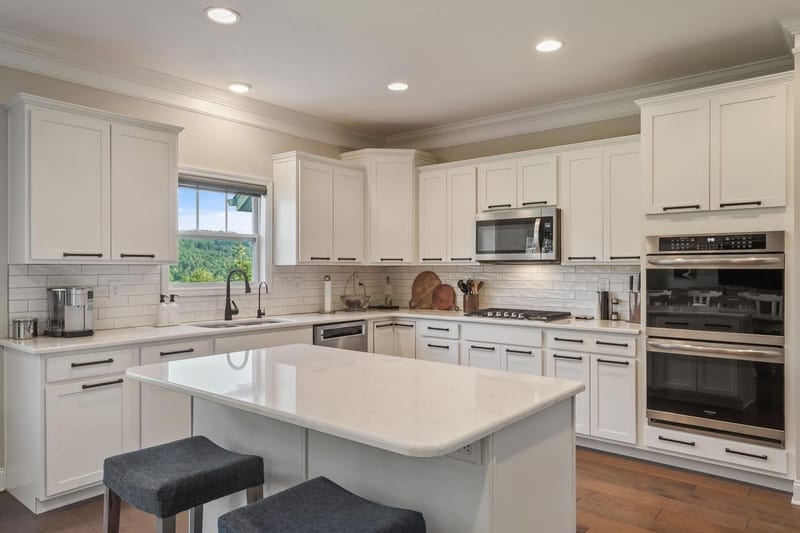 White farmhouse kitchen with quartz island and a view window over the sink