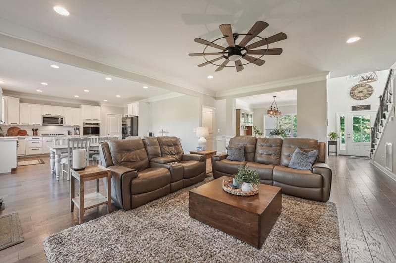 Open-concept living room sweeping into the kitchen under windmill ceiling fans