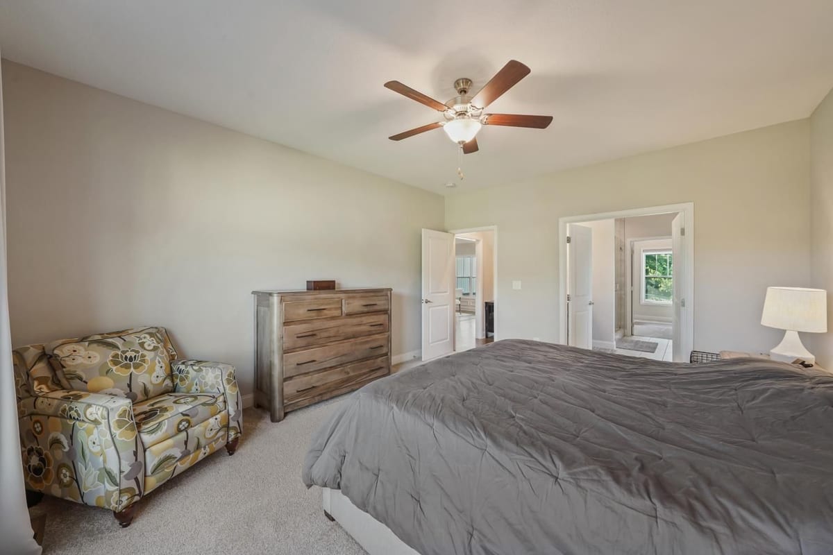 Owner suite bedroom with ceiling fan and soft corner light (detail crop)