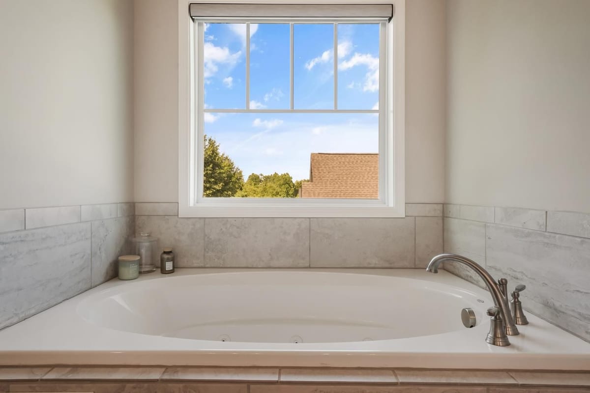 Freestanding soaking tub beneath a bright window (detail crop)