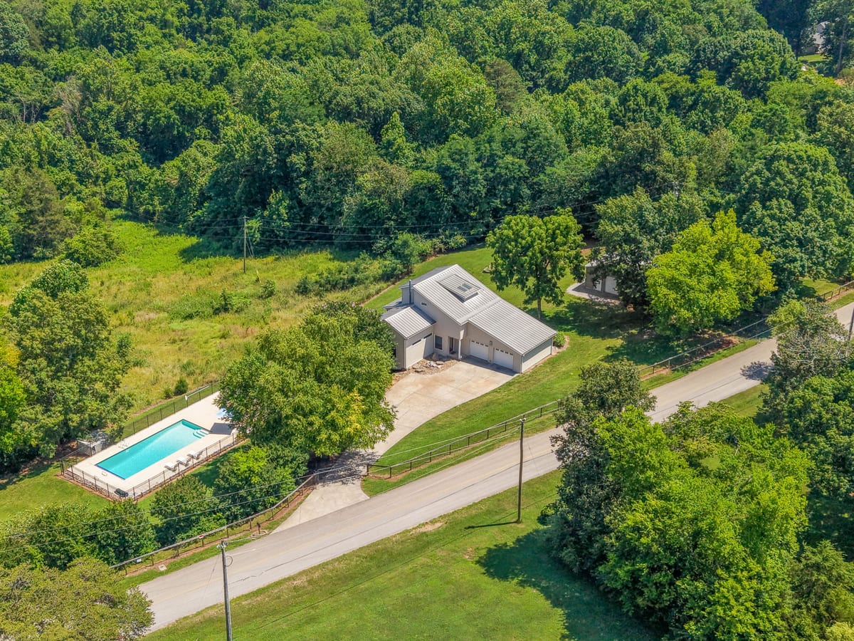 Drone aerial of the home, drive, and pool in a wooded clearing