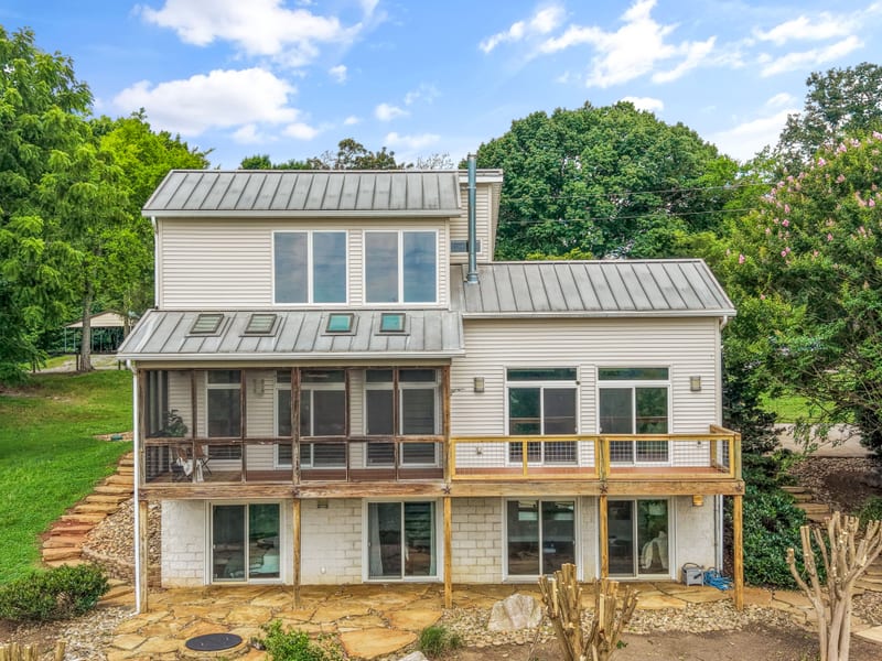 Contemporary home with standing-seam metal roof and glass gables above a stone path