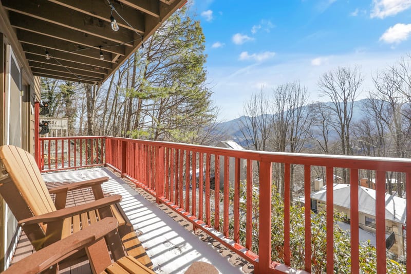 Adirondack chairs on a snow-dusted cabin deck facing the mountains
