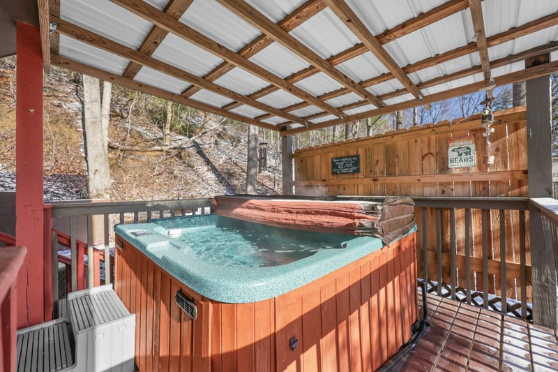Steaming hot tub on a covered cabin deck in winter light
