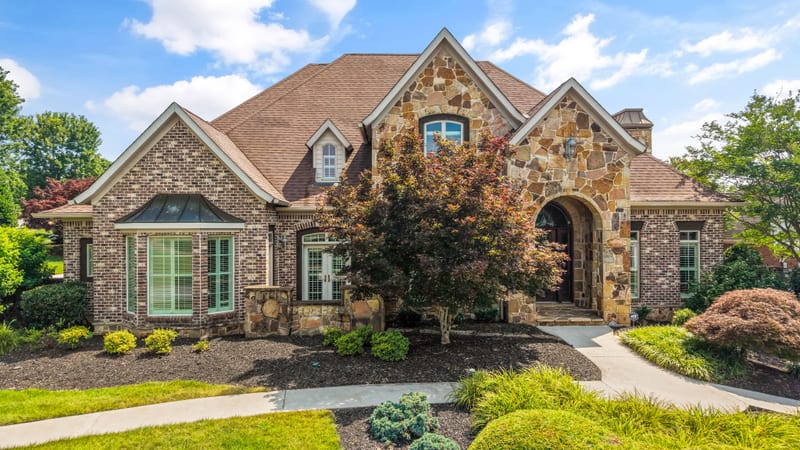 Stone and brick manor with arched turret entry and a Japanese maple