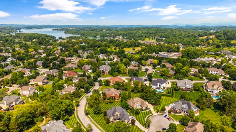 Drone aerial over the neighborhood toward a distant lake vista