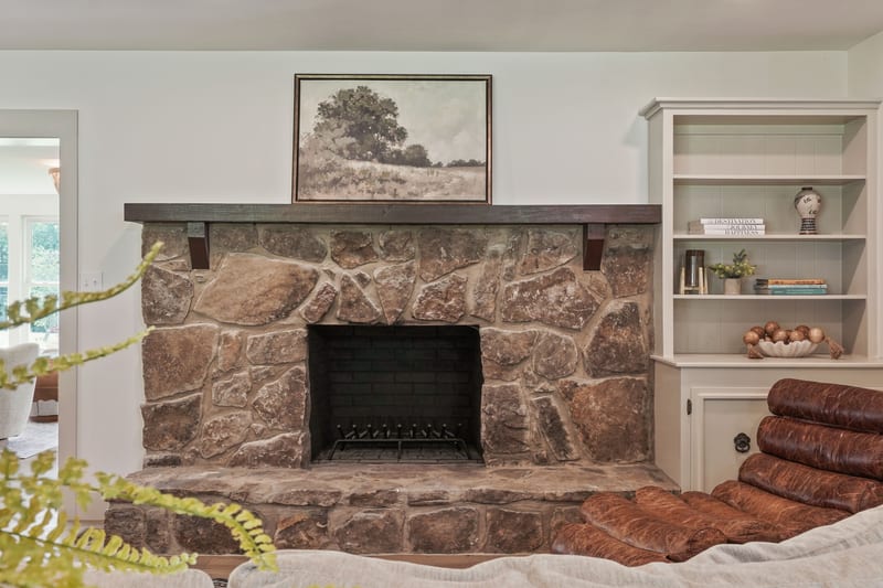 Stone fireplace with wood mantel beside a leather lounger