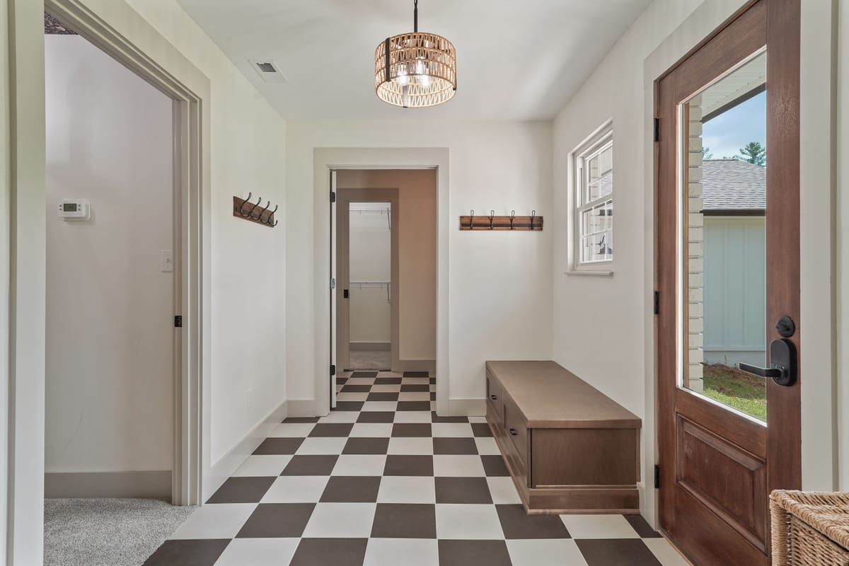 Mudroom entry with checkerboard floor and antique wood door