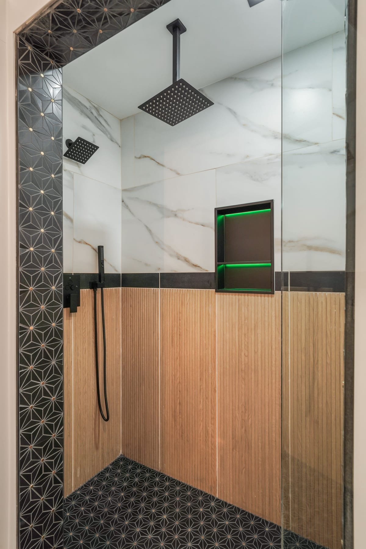 Black-marble walk-in shower with wood accent wall (detail crop)