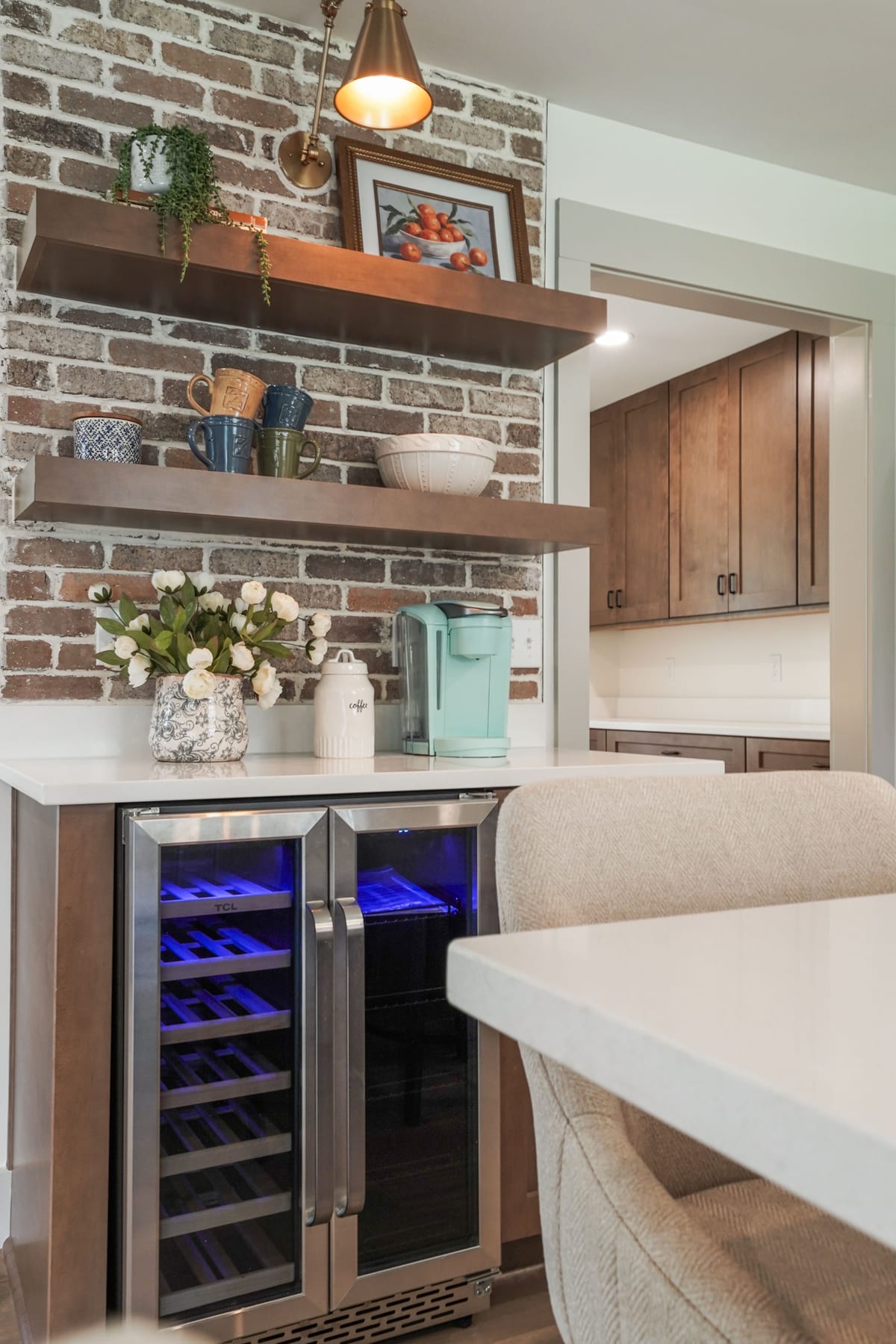 Wine fridge below open shelving set into exposed brick (detail crop)